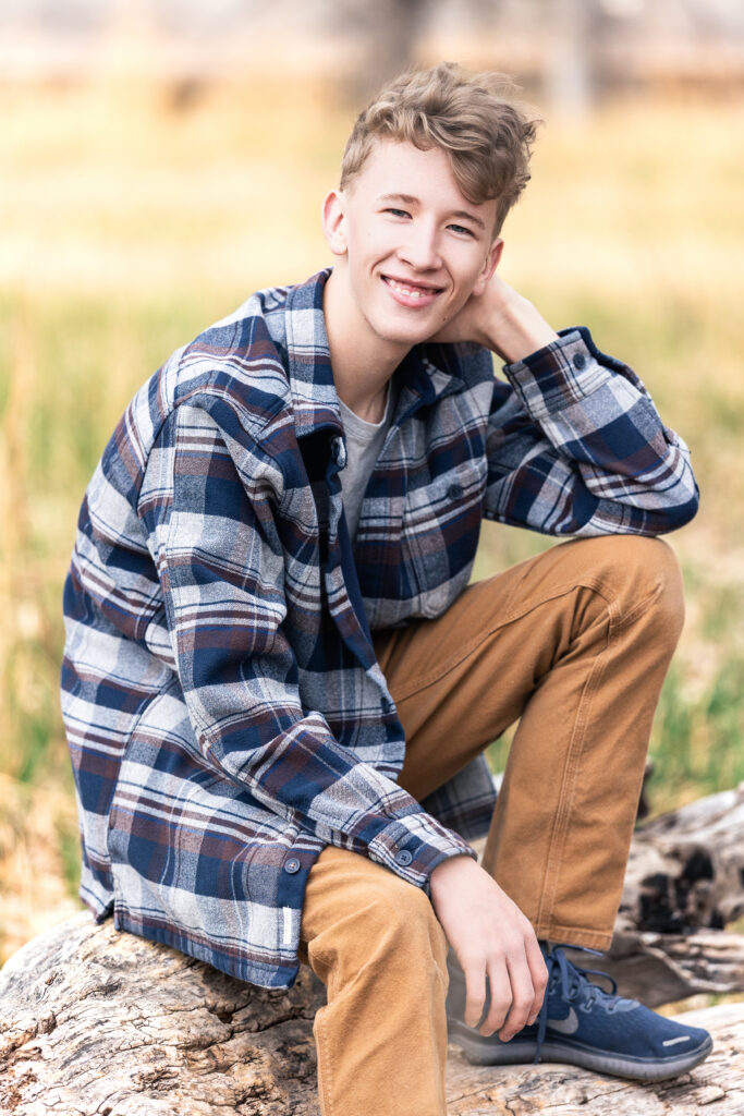 Colorful senior photo of teen guy smiling outdoors, selected for his school’s senior slideshow, captured by Northern Colorado senior photographer Heather Lilly