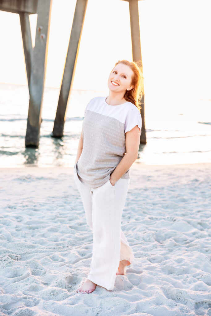 Heather Lilly standing barefoot on a Florida beach during sunset, attending a photography conference as a lifelong learner and creative entrepreneur
