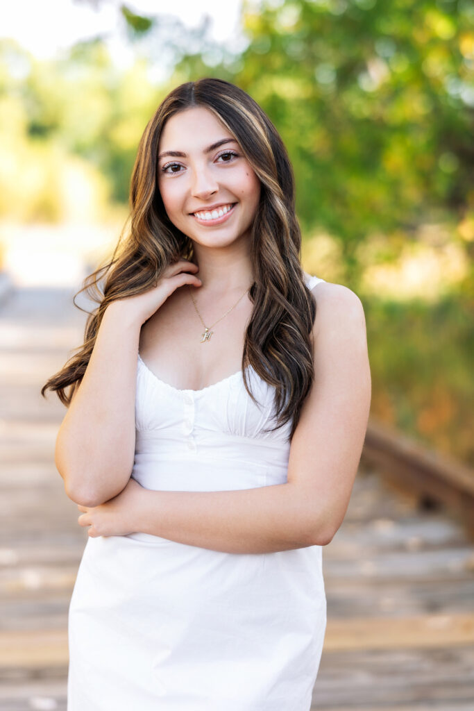 Senior portrait of a teen girl in a classic white dress walking a path at Signature Bluffs in Greeley, photographed by Northern Colorado senior photographer Heather Lilly