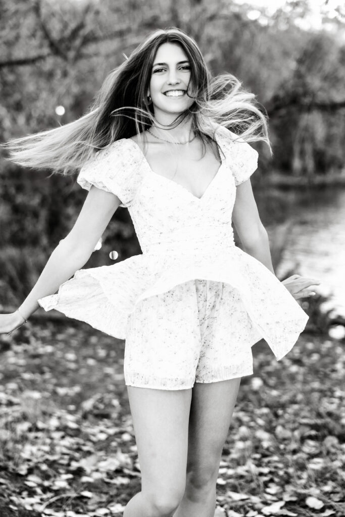 Black and white senior portrait in Greeley CO with twirling dress and motion-filled hair, captured during a joyful moment outdoors.