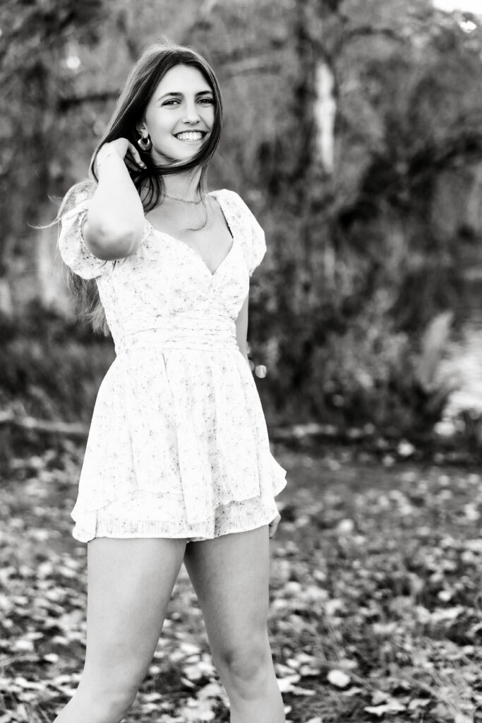 Black and white senior portrait in Greeley CO with joyful expression and wind-blown hair, natural light photography for Class of 2025