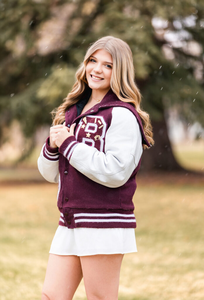 Senior girl in letterman jacket during cap and gown photo session