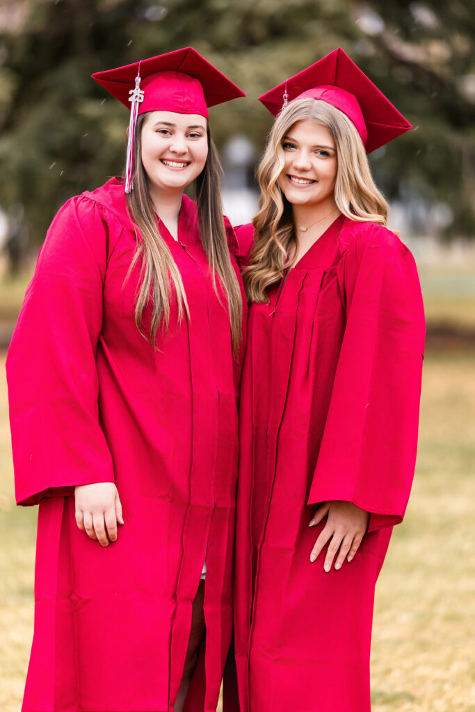 Spring senior portraits of best friends in cap and gowns, smiling together during a cap & gown mini session by Heather Lilly Photography in Northern Colorado