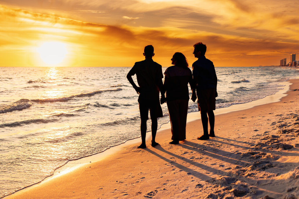 Sunset silhouette of Northern Colorado photographer Heather Lilly with her sons, walking along the shoreline in Florida during a photography conference travel session