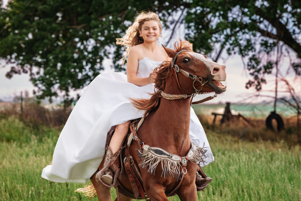 Teen girl riding a horse in a white dress during an equestrian portrait session in Eaton, Colorado at sunset, captured by Northern Colorado photographer Heather Lilly