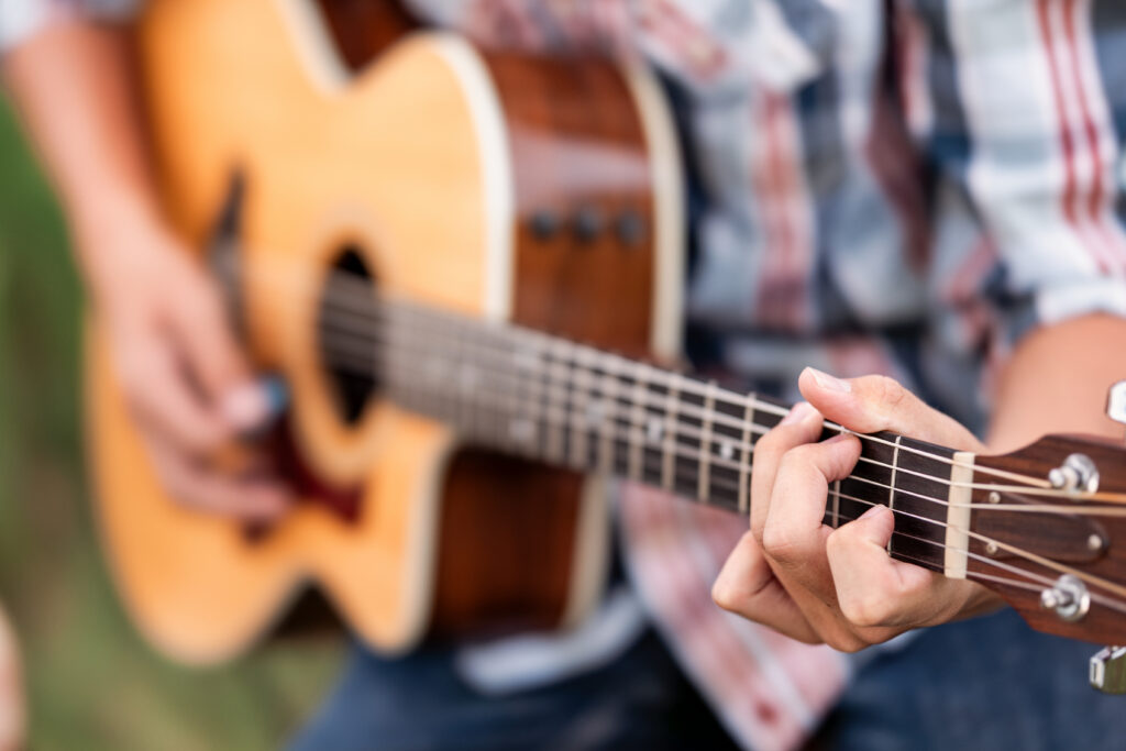 Close-up of teenage boy’s hands playing acoustic guitar during a country music portrait session in Northern Colorado