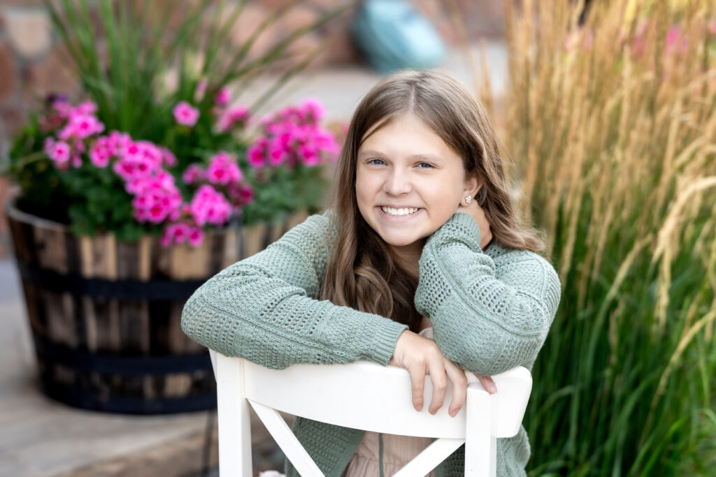 Tween girl smiling during back-to-school portrait session in NoCo with natural light and floral background