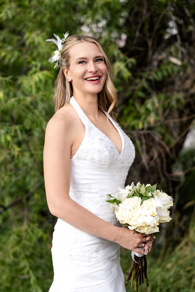 Bride holding bouquet and smiling during her 15-year anniversary portraits at Lions Park in Cheyenne, Wyoming, captured by Heather Lilly Photography.