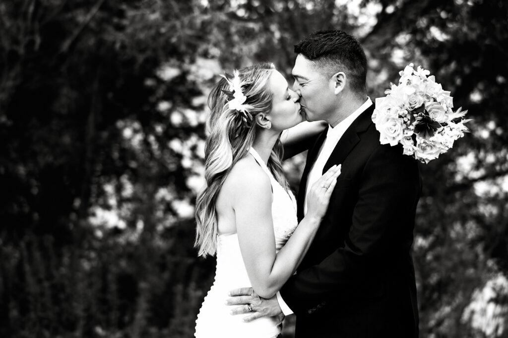 Husband and wife kissing during their 15-year anniversary portraits at Lions Park in Cheyenne, Wyoming — a recreation of their 2010 wedding photo, captured by Heather Lilly Photography.