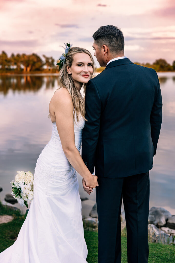 Wife smiling while holding hands with her husband at sunset during their 15-year anniversary portraits at Lions Park in Cheyenne, Wyoming, captured by Heather Lilly Photography.