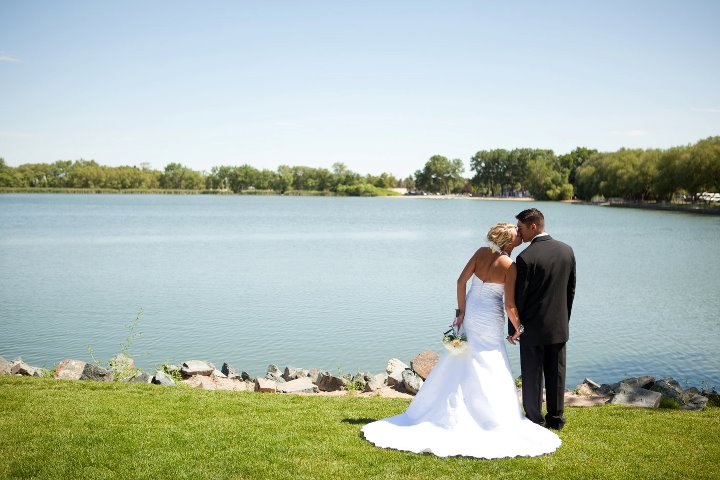 Husband and wife kissing by the lake during wedding at Lions Park in Cheyenne, Wyoming ,captured by Heather Lilly Photography.