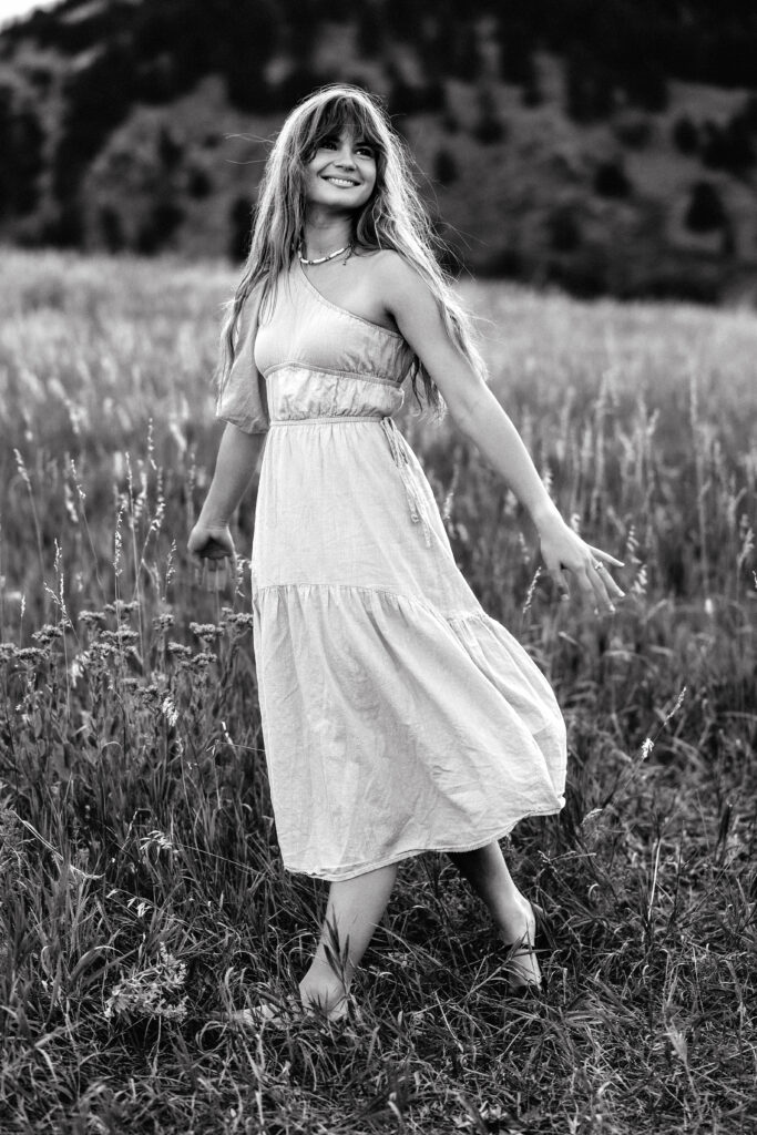 Smiling black and white portrait of Eden Alley, Colorado photographer, in natural outdoor setting.