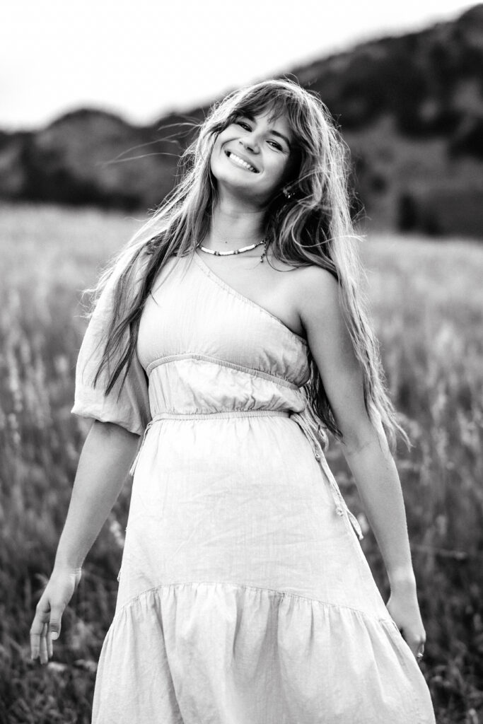 Classic monochrome portrait of Colorado wedding photographer Eden Alley with relaxed pose in meadow.