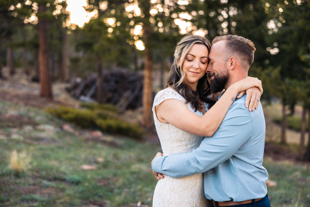 Husband and wife holding each other during vow renewal at Lily Lake in Estes Park Colorado, photographed by Northern Colorado photographer Heather Lilly at golden hour in the mountains.