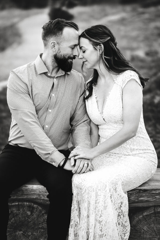 Husband and wife praying & holding hands during vow renewal at Lily Lake in Estes Park Colorado, photographed by Northern Colorado photographer Heather Lilly at golden hour in the mountains. Black & white photo. 