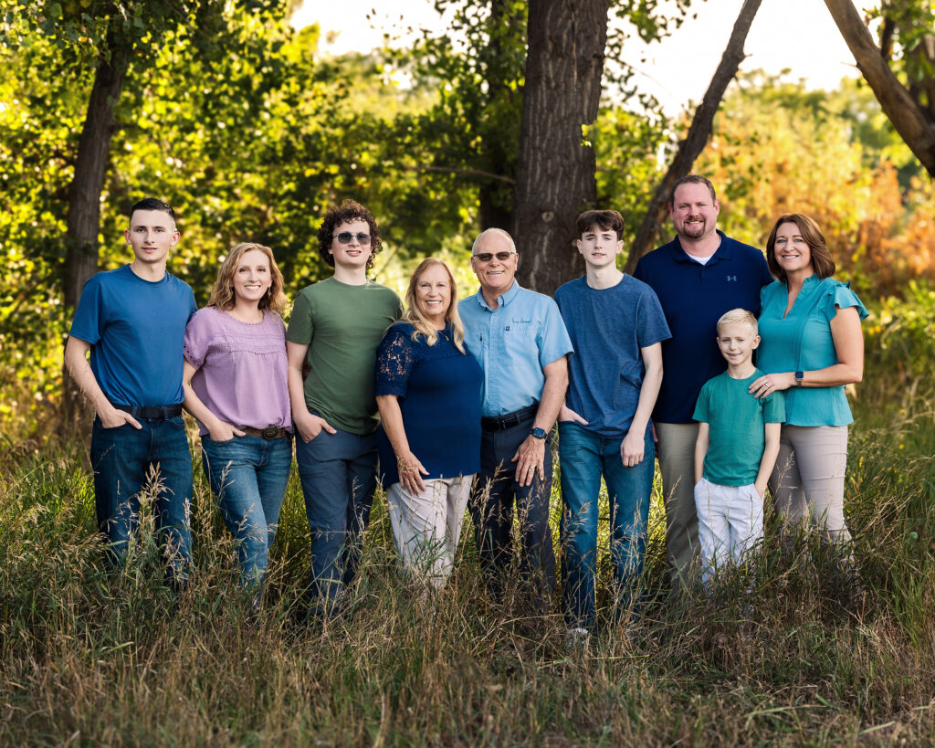Extended family standing together in early fall light in Northern Colorado, smiling during their annual portrait session with Heather Lilly Photography.