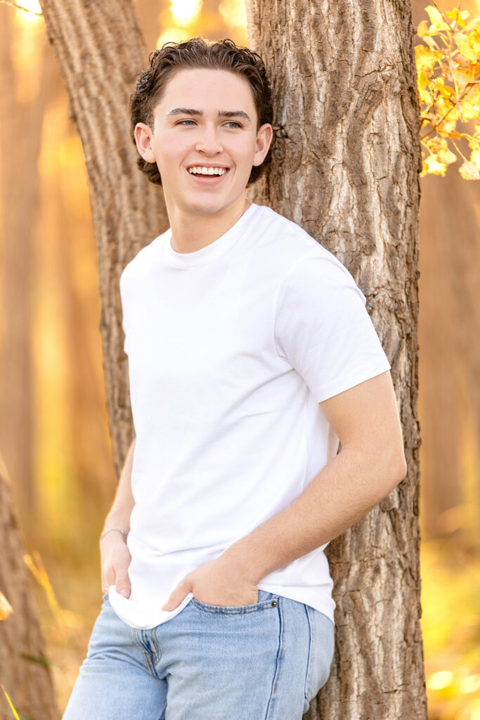 Close-up portrait of a young man smiling in golden light, Northern Colorado senior photographer specializing in authentic fall sessions.